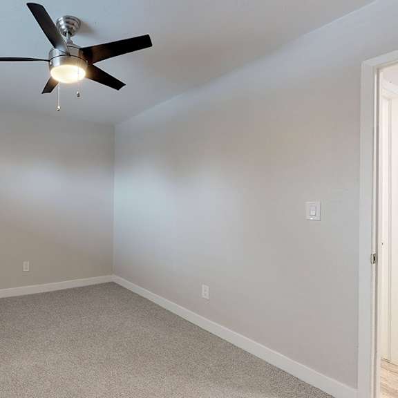 a room with a ceiling fan and carpeted floor.