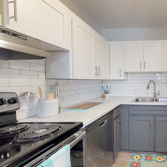 a kitchen with a stove, sink, and refrigerator.