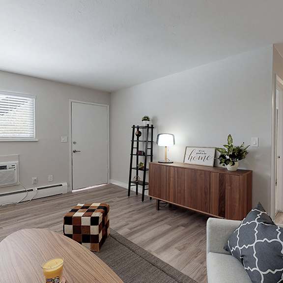 a living room with a couch, a coffee table, and a window with blinds.