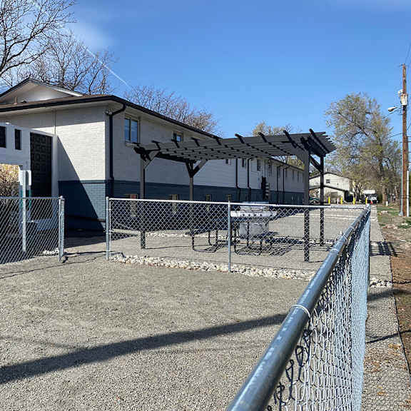 fenced-in dog run with pergola in the background.