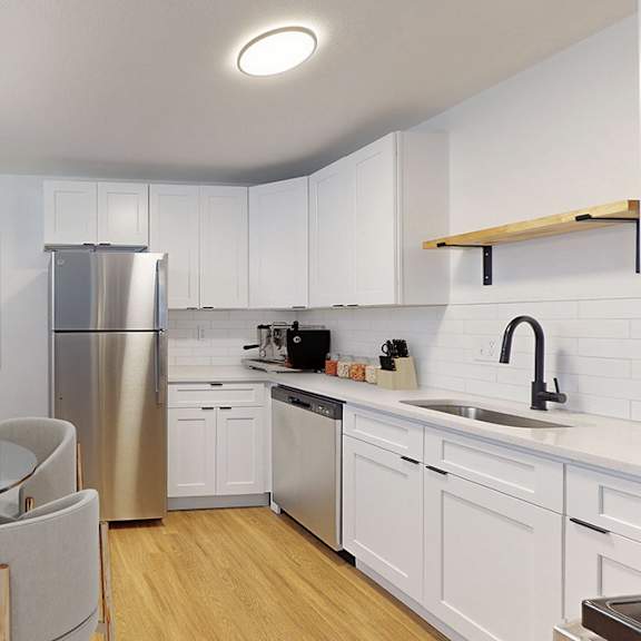a modern kitchen with a glass dining table and stainless steel appliances.