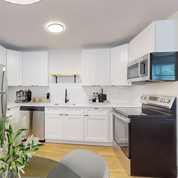 a modern kitchen with white cabinets and stainless fridge, dishwasher, microwave and range.