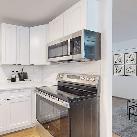a modern kitchen with white cabinets and stainless steel appliances including dishwasher, microwave and range.