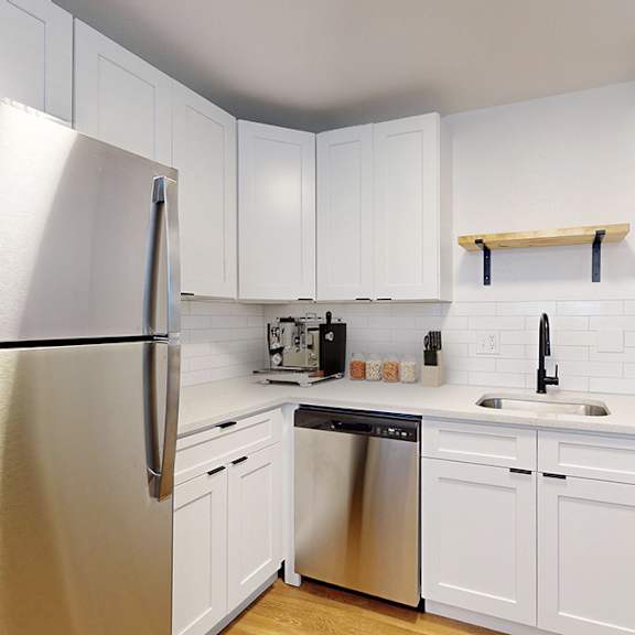 a kitchen with white cabinets and a stainless steel refrigerator and dishwasher