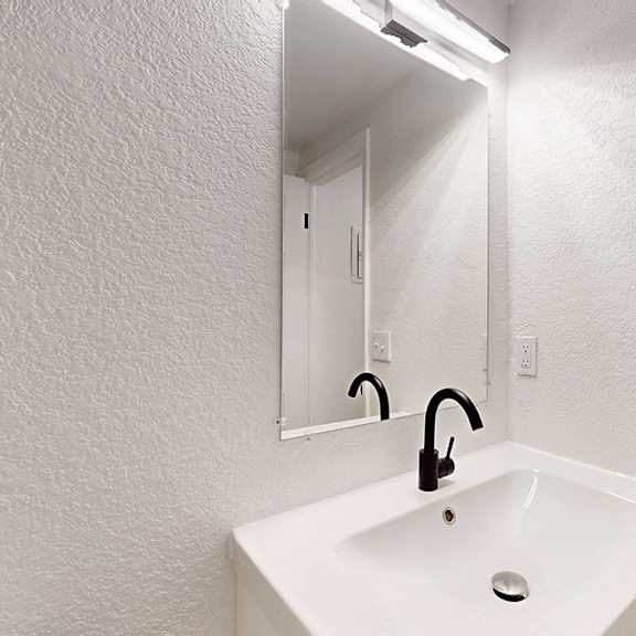 a white sink in a bathroom with mirror and modern lighting.