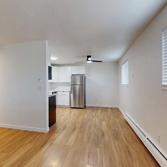 a living room with wooden floors and a view of dining and kitchen area.