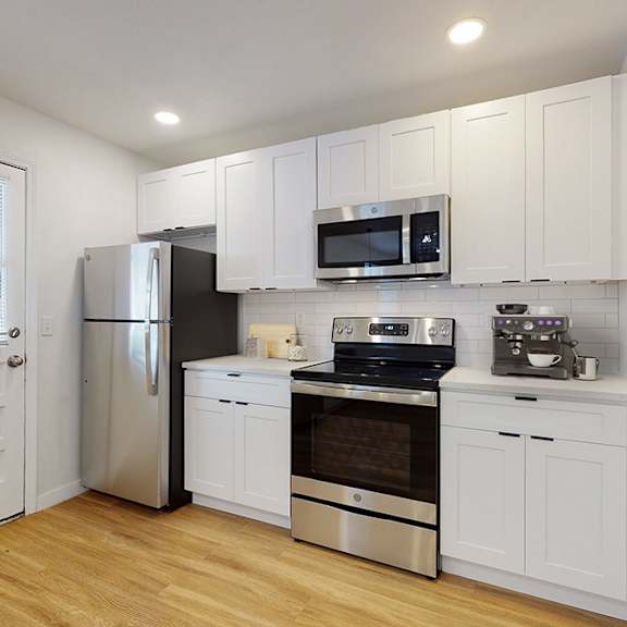 a kitchen with white cabinets and stainless steel appliances.
