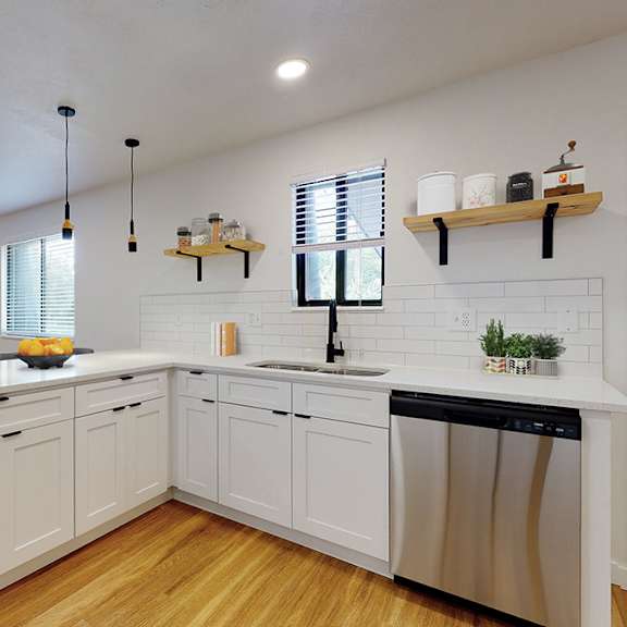 a modern kitchen with white cabinets and a wooden floor.
