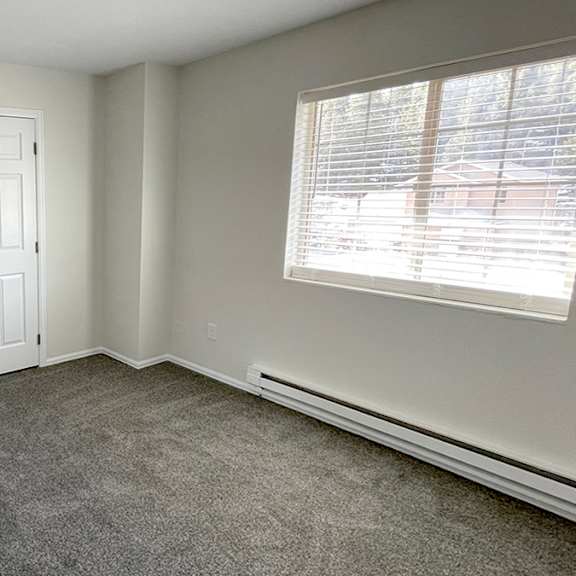 a room with a carpeted floor and a window with blinds.