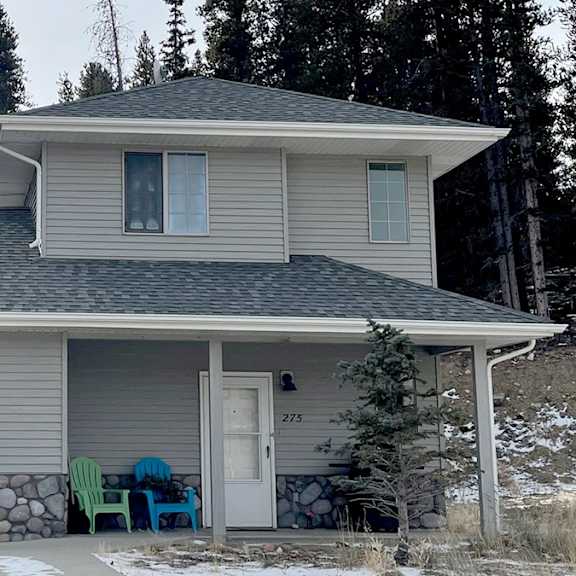 a house with a garage and a porch with chairs.