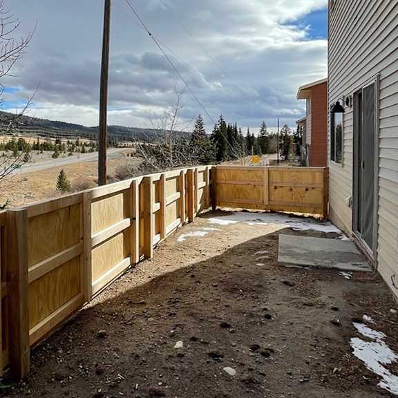 a wooden fence runs along the side of a building.