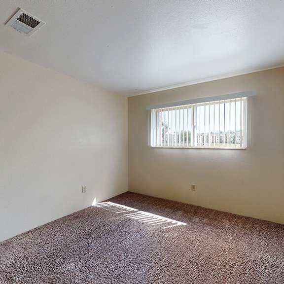 a room with a window and a carpeted floor.