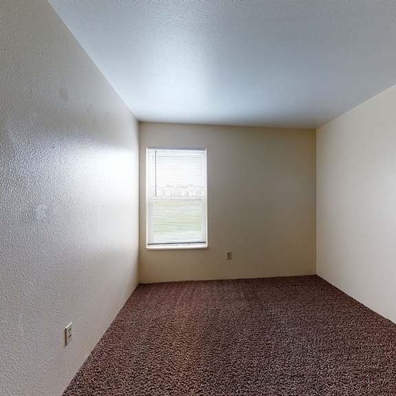a room with a window and carpeted floor.