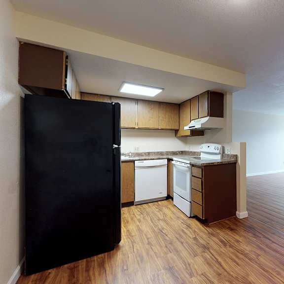 a kitchen with a black fridge and wooden floors.