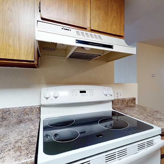 a white stove top oven with a silver handle is in a kitchen with wooden cabinets.