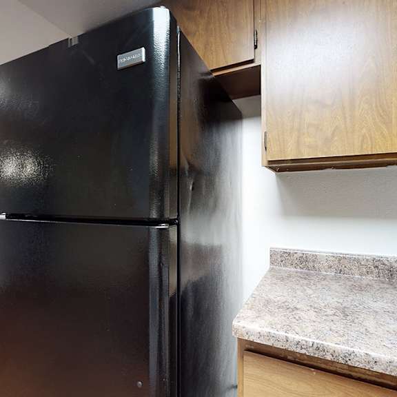 a black refrigerator in a kitchen with wooden cabinets.