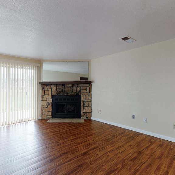 a living room with a fireplace and wood flooring.