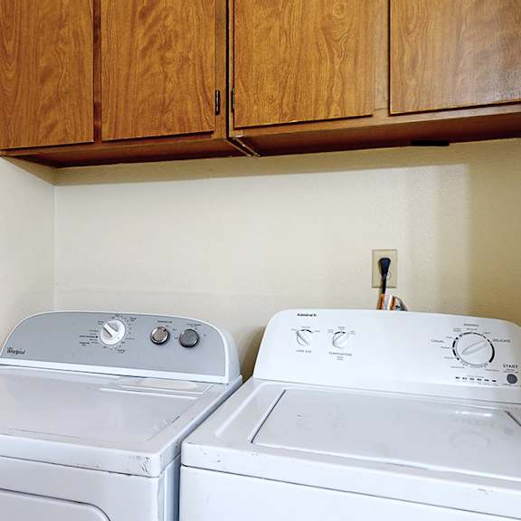 two white washing machines in a laundry room.
