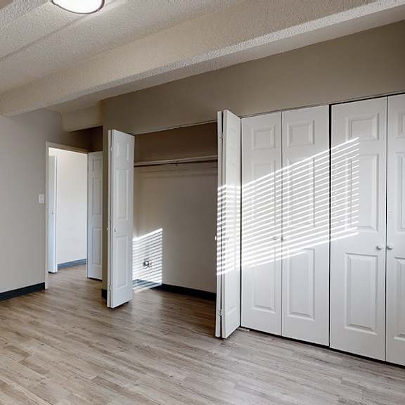 a room with a white wall and a wooden floor with a white closet.