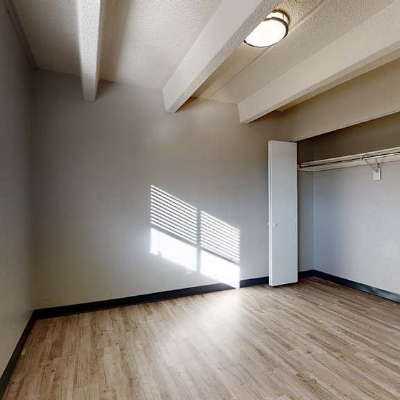 a room with wooden flooring and a window with blinds.