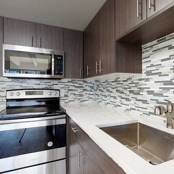 a modern kitchen with a stove, oven, microwave, and a sink.