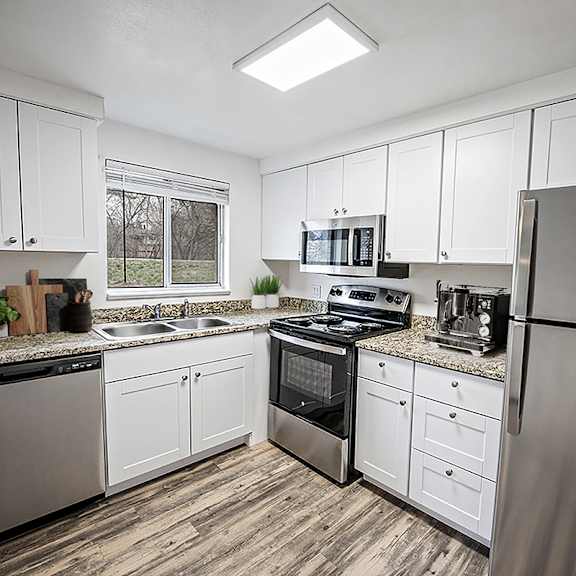 a kitchen with white cabinets and stainless steel appliances.
