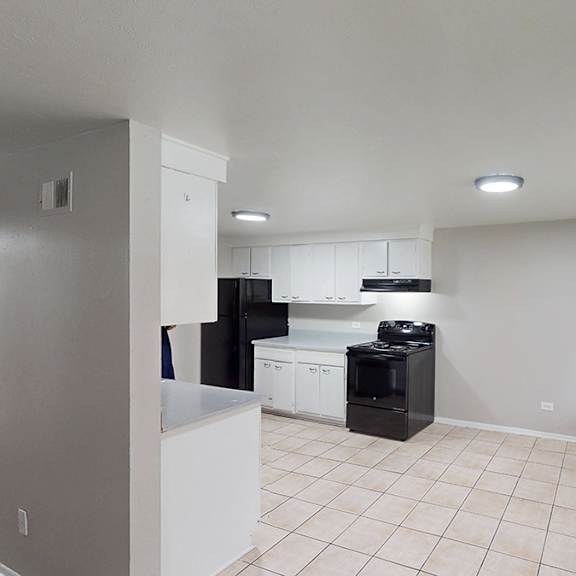 a kitchen area with a black fridge, white cabinets, and a black stove top oven.