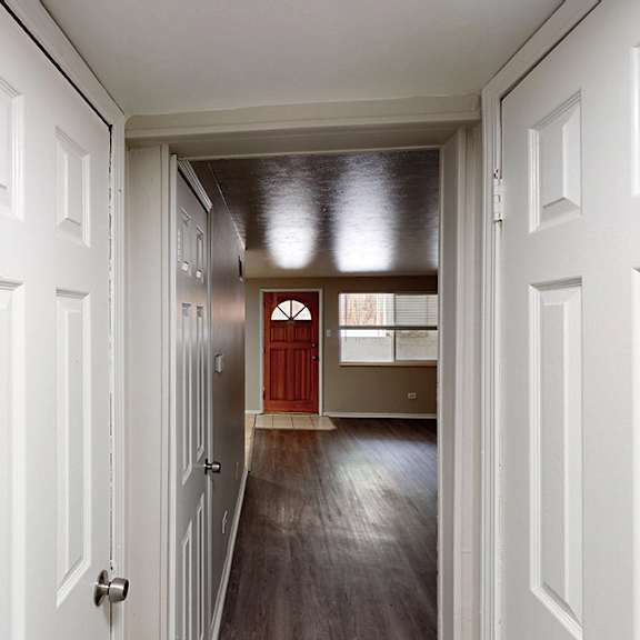 a hallway with white doors on both sides leading to a red door.
