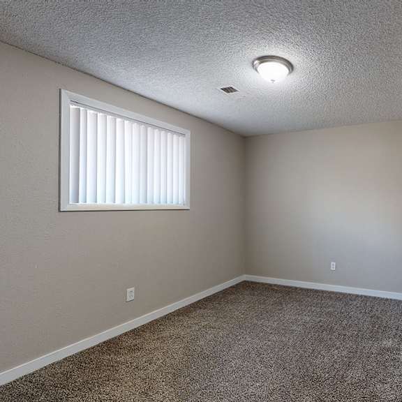 a room with a carpeted floor, a door, and a window with blinds.