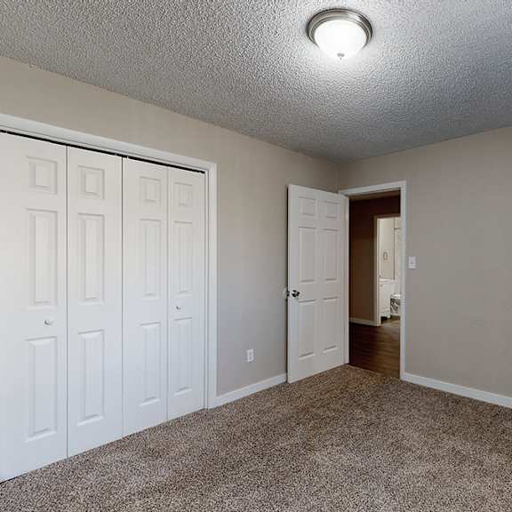 a room with a carpeted floor and two doors.