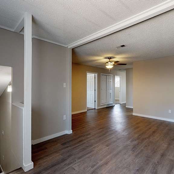 a spacious room with wood flooring and a ceiling fan.
