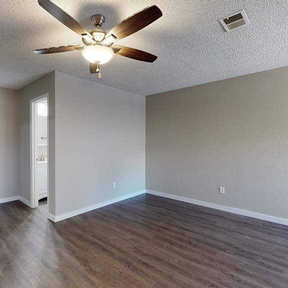a room with a ceiling fan and wooden flooring.