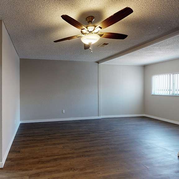 a room with a ceiling fan and a toilet in the corner.