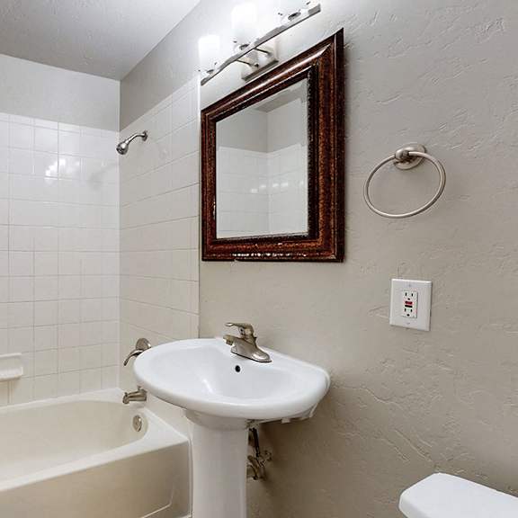 a white bathroom with a white tub, sink, and toilet.