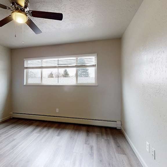a room with a ceiling fan and a window with a view of trees.