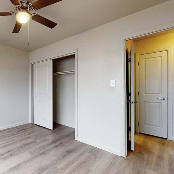 a room with a ceiling fan and light, a door, and a window.