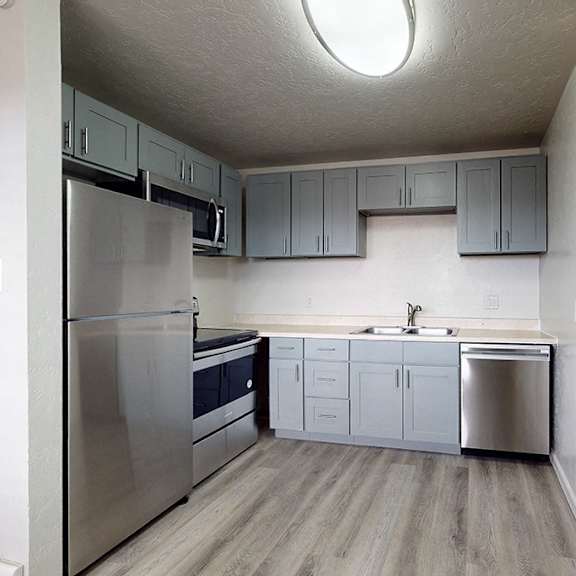 a kitchen with a refrigerator, sink, and cabinets.