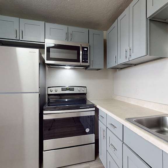 a kitchen with a stainless steel refrigerator, microwave, oven, and sink.