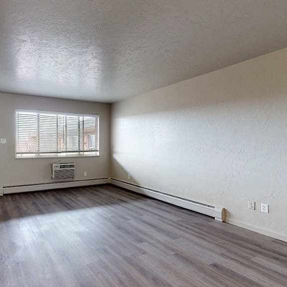 a room with a wooden floor and a window with blinds.