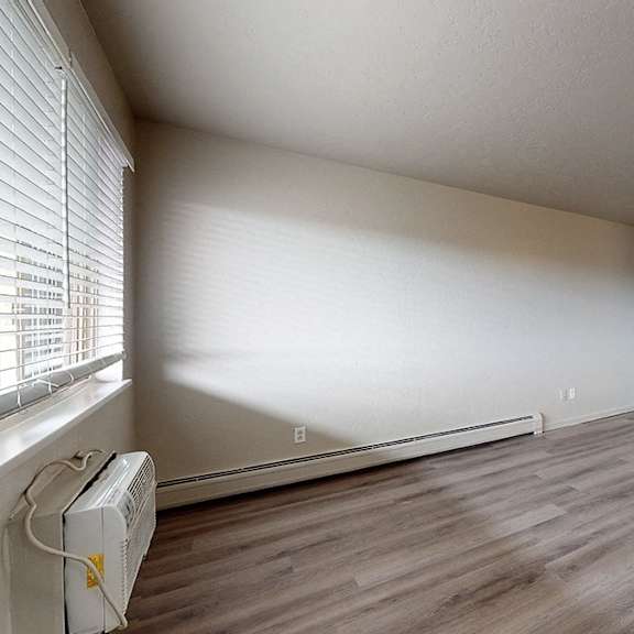 a room with wooden flooring and a window with blinds.