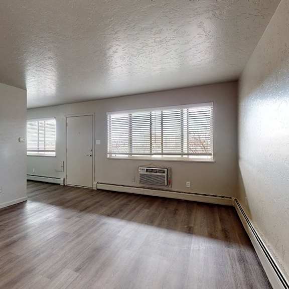 a room with wooden floors and a window with blinds.