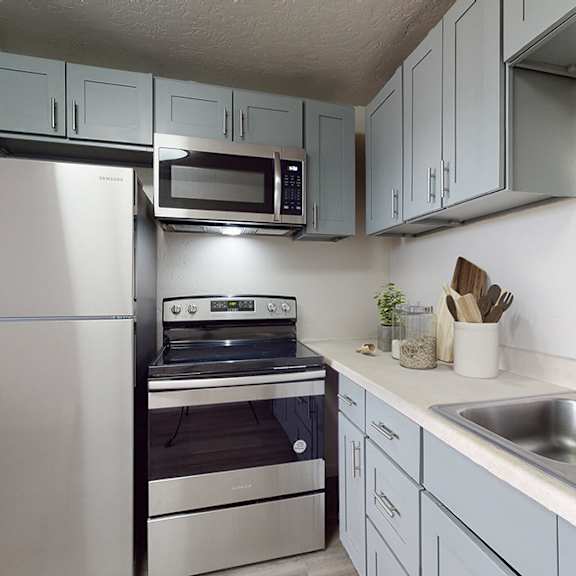 a kitchen with a stainless steel refrigerator, microwave, and oven.
