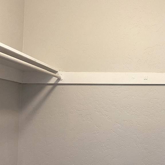a white wall with a white shelf on it.