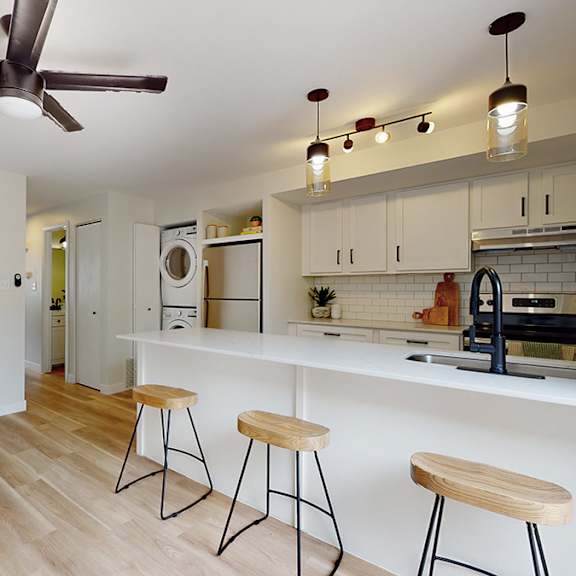 a kitchen with a white counter and bar stools.