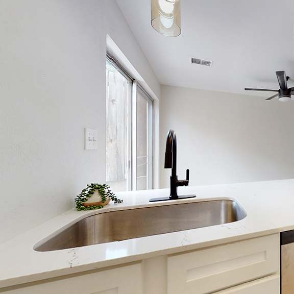 a modern kitchen with a stainless steel sink and a black faucet.