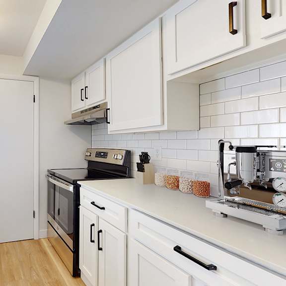 a kitchen with white cabinets and a black stove top oven.