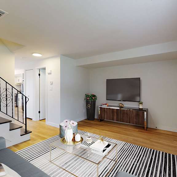 a living room with a staircase and a television.