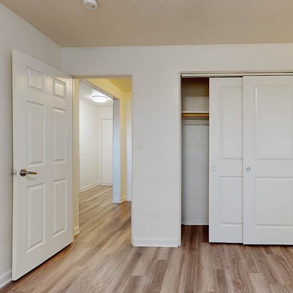 a room with white doors and wooden floors.