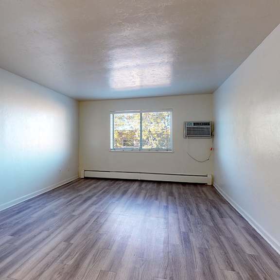 a room with wooden flooring and a window with blinds.