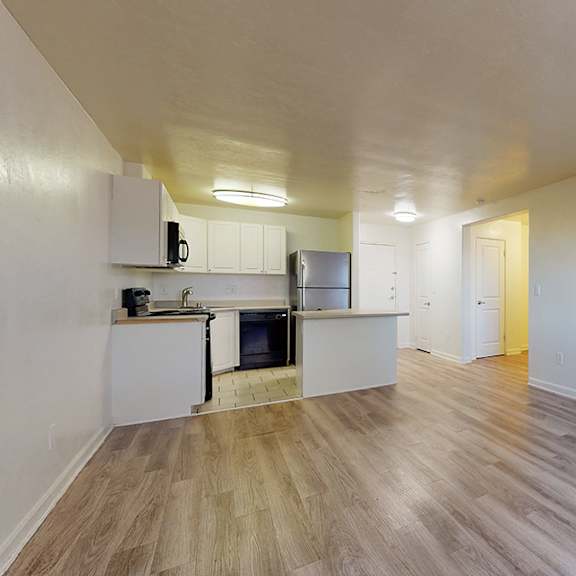 a spacious room with a kitchen area and a door on the right.